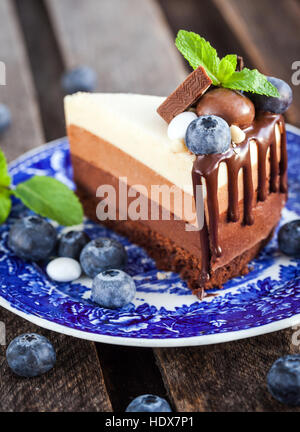 Pezzo di tre deliziosa mousse al cioccolato torta decorata con mirtilli freschi, menta e caramelle Foto Stock