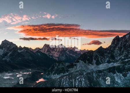 Vista aerea da Gokyo Ri (5360m) con una grande nuvola rossa all'alba, le montagne coperte di neve in lontananza Foto Stock