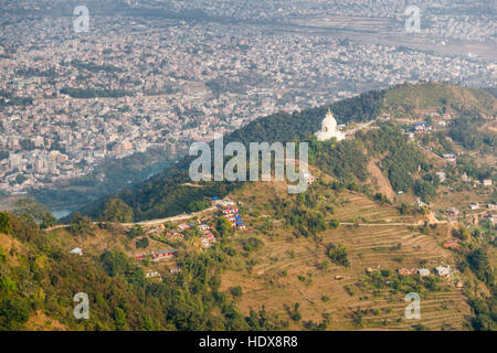 Vista aerea su un villaggio locale e la pace nel mondo stupa, pokhara e alcune montagne in distanza Foto Stock