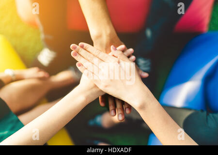 Tre giovani uomini di affari di unire le vostre mani in team, il lavoro di squadra o unity concetto, multi-etnico gruppo diversità, una luce calda e effetto di profondità di campo Foto Stock