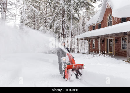 Uomo con un ventilatore di neve la cancellazione di una strada in una bella stagione invernale innevato paesaggio di Muskoka, Ontario, Canada Foto Stock