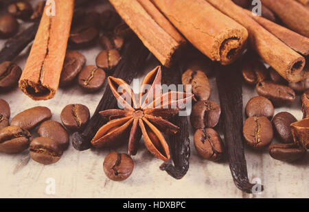 Foto d'epoca, fresco e fragrante baccelli di vaniglia, bastoncini di cannella, anice stellato e grani di caffè sul vecchio rustico di legno, condimenti per cookin Foto Stock