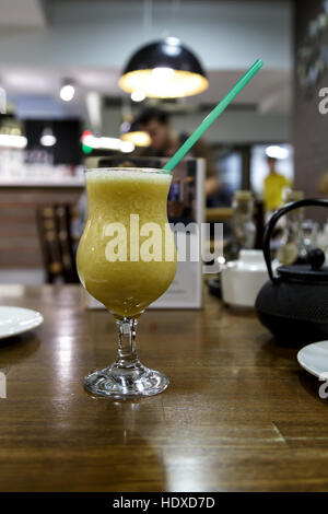 Bere frullati in un bicchiere su un tavolo contro il cafe Foto Stock