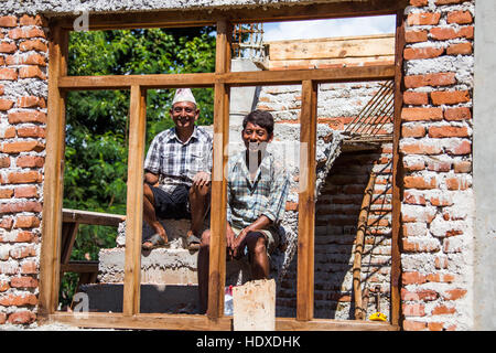 Proprietario di casa (sinistra) e le ONG addestrato mason la ricostruzione di una casa utilizzando i metodi più sicuri, Nuwakot distretto del Nepal Foto Stock