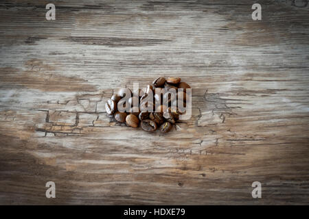 Forma di cuore fatta da chicchi di caffè su sfondo di legno. Foto Stock