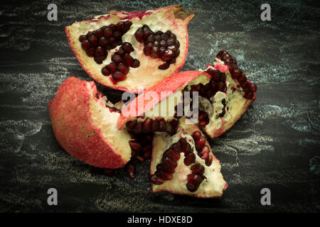 Melograno frutta tagliata a metà su sfondo scuro, mostrando semi rosso. Mangiare sano, la dieta o il concetto di cucina a vista. Cibo vegan. Materie Foto Stock