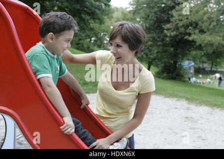 Giovane madre e figlio, bambino nel parco giochi Foto Stock