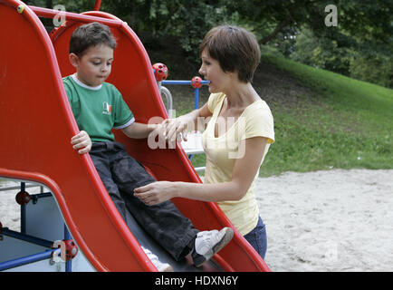 Giovane madre e figlio, bambino nel parco giochi Foto Stock