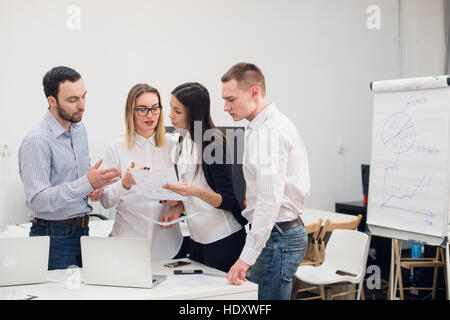Il gruppo di quattro diversi uomini e donne in abbigliamento casual parlando in ufficio Foto Stock