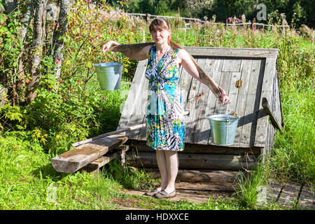 Giovane donna attraente vicino al villaggio di legno e acqua in estate giornata di sole Foto Stock