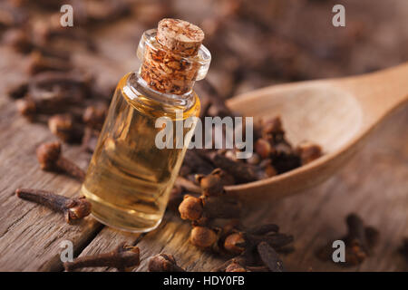 Olio di chiodi di garofano in una bottiglia di close-up sul tavolo. orizzontale, stile rustico Foto Stock