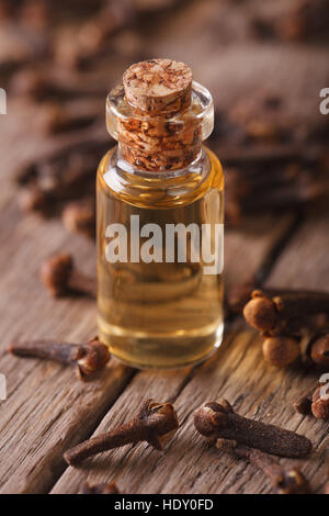 Olio di chiodi di garofano in una bottiglia di vetro su una tabella macro verticale. Foto Stock