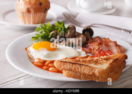 Uova fritte con pancetta e fagioli su una piastra di close-up orizzontale. Foto Stock