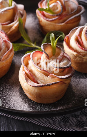 Cibo sano: la torta di mele nella forma di rose su una piastra nera macro verticale. Foto Stock