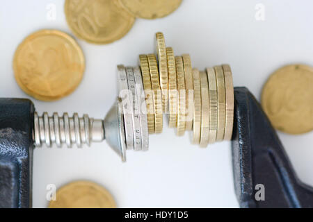 Economia concetto di pressione con la pila di monete in un crampi Foto Stock