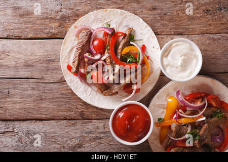 Tortilla con carne e verdure e salsa sul tavolo. vista orizzontale dal di sopra Foto Stock
