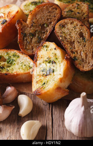 Fette di pane tostato con erbe e aglio closeup sul tavolo. Verticale, stile rustico Foto Stock