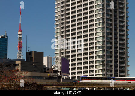 Tokyo Tower dietro gli edifici di appartamenti e un treno della linea Yurikamome a Tokyo, Giappone Foto Stock