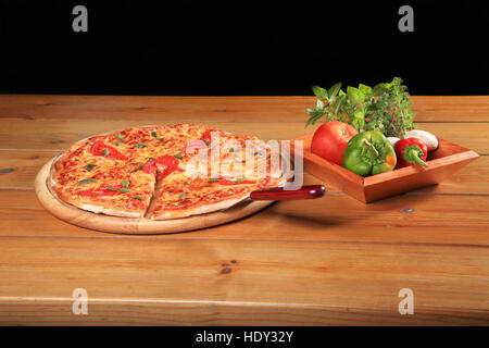 Pizza Fresca margarita su una lastra di legno e ciotola con verdure Foto Stock