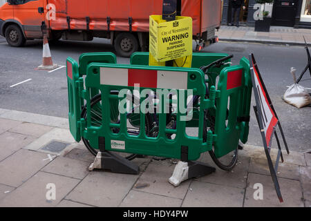 Una bicicletta è stato recintato tra alcune barriere architettoniche e al di sotto di una sospensione di parcheggio cartello segnaletico in Bond Street, il 15 dicembre 2016, a Londra, in Inghilterra. Foto Stock