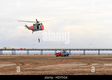 Royal Navy Seaking Ricerca e Salvataggio in elicottero di eseguire la simulazione di soccorso con equipaggio appeso dal verricello Foto Stock