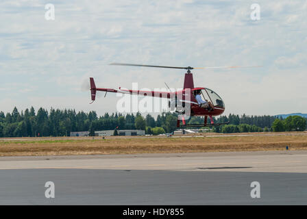 Due-passeggeri Robinson R22 elicottero tenendo fuori dal campo di aviazione. Foto Stock