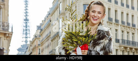 Bollente invernale alla moda di Parigi. Ritratto di felice donna moderna con albero di Natale a Parigi, Francia Foto Stock