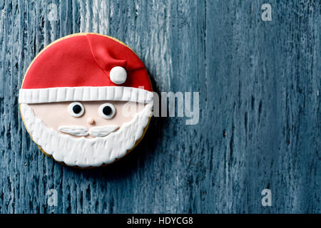 Alta angolazione di un cookie di natale nella forma del viso di Babbo Natale su un livello di grigio in legno rustico in superficie, con un spazio negativo Foto Stock