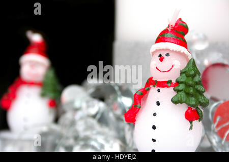 Pupazzo di neve: pupazzo vestito di sciarpa e hat portando ad albero di natale candela Foto Stock