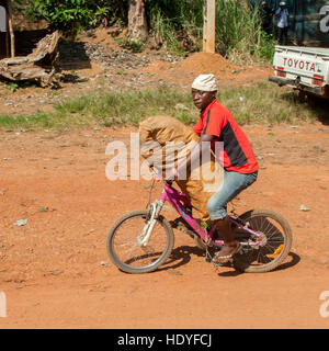 Giovane uomo con un grande sacco su una piccola bicicletta Foto Stock