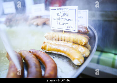 Il tempo di avvento nel centro della città di Zagreb, Croazia. Famoso fast food durante il tempo di Avvento, salsicce fryed nell'olio a un cibo stand. Foto Stock