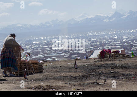 Una donna boliviana tende ad una mesa, l'offerta alla Pachamama o madre terra Dio in Bolivia con le montagne sullo sfondo Foto Stock