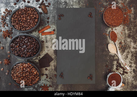 Diversi tipi di caffè, cioccolato e spezie sul tavolo rustico con lavagna in ardesia. Vista dall'alto, uno spazio vuoto, vintage tonica Foto Stock