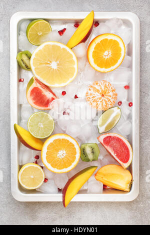 Varie fette di agrumi e di altri frutti nel vassoio di metallo su ghiaccio. Vista dall'alto, uno spazio vuoto Foto Stock