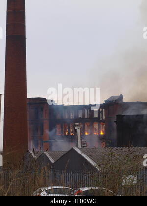 Oldham, Regno Unito. 15 Dic, 2016. Servizi di emergenza hanno evacuato più di 100 nelle vicinanze proprietà dopo un grande incendio scoppiato in un mulino di carta sito nella Greater Manchester. Più di 70 vigili del fuoco e 15 motori fire da Greater Manchester Fire e servizio di soccorso sono combattere l'incendio dell'edificio sulla strada Cardwell in Oldham, a nord-est di Manchester, il giovedì mattina. © M Kyle/Alamy Live News Foto Stock