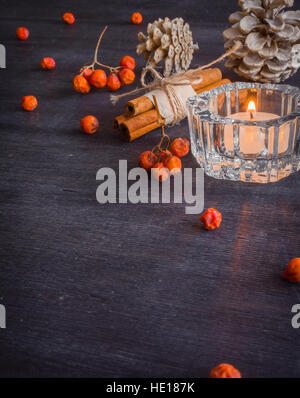 Scuro dello sfondo di Natale con le candele e le bacche del sorbo. Pino bianco coni. Rami ghiande. Foto Stock