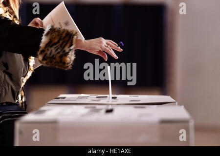 Mano con un timbro colata di un voto nell'urna durante le elezioni Foto Stock