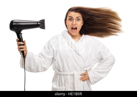 Scioccato la donna in un accappatoio asciugando i capelli con un asciugacapelli isolati su sfondo bianco Foto Stock