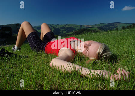 Donna bionda, 22, giacente in erba e godere il paesaggio estivo dopo una escursione, Laussa, Austria superiore, Austria, Europa Foto Stock