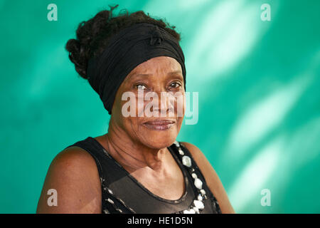 Vecchio popolo cubano e di emozioni, ritratto di felice senior african american lady guardando la fotocamera. Copia spazio sulla parete verde in background. Foto Stock