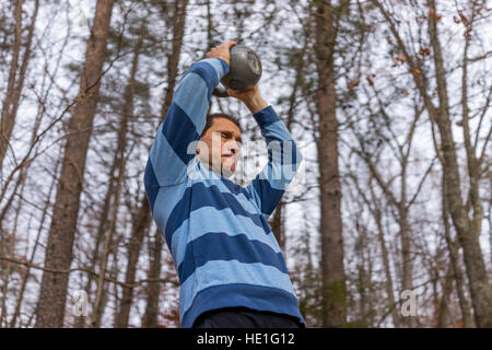 L'uomo il sollevamento di un carico pesante kettlebell sopra la testa con difficoltà Foto Stock