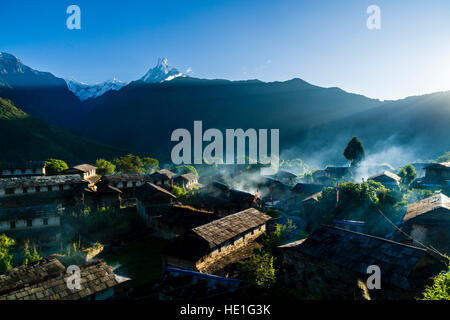 Vista sul borgo storico con la montagna machapuchare nella distanza di sunrise, smog è venuta fuori delle case Foto Stock