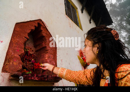 Una donna sta offrendo prasad per le statue di divinità al di fuori del tempio khadga devi mandir presso il festival indù, darsain Foto Stock