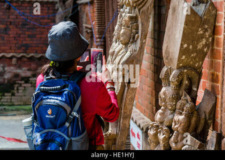 Una donna cinese è scattare una fotografia del abilmente intagliata in legno figure a hanuman dhoka palace Foto Stock