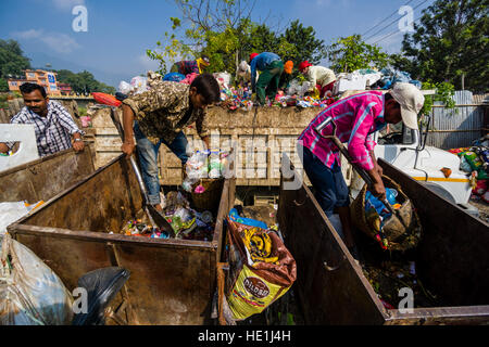 Le persone sono la raccolta di rifiuti in città, il carico su camion e trasporto ad una discarica di rifiuti al di fuori della città Foto Stock