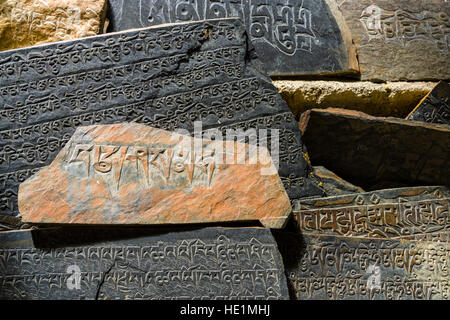 Mani pietre con inciso il mantra tibetano Om mani padme hum sono impilati fino a una parete Foto Stock