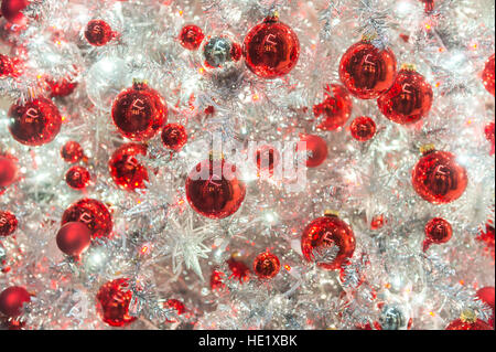 Rosso lucido ornamenti vacanze decorare un moderno argento lucido albero di Natale in un frame completo sullo sfondo di close-up Foto Stock
