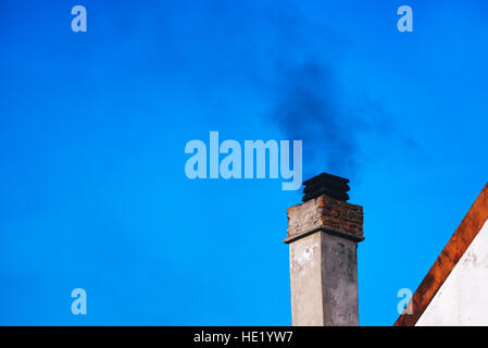 Il fumo dal camino di casa sulla giornata invernale Foto Stock