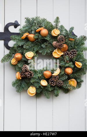 Decorativa ghirlanda di Natale appeso a un bianco dello sportello anteriore. Foto Stock