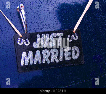 Appena sposato segno appeso sulla parte posteriore di un blu vintage auto nozze sotto la pioggia. Foto Stock